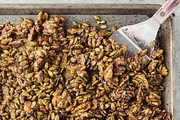baked candied rosemary walnuts and pumpkin seeds on a baking sheet