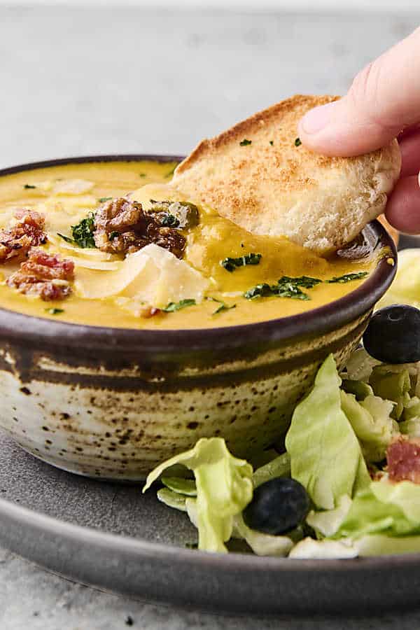 dunking bread into pumpkin soup