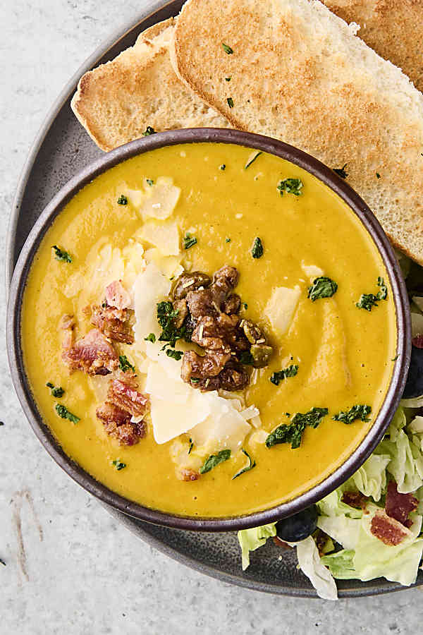 creamy pumpkin soup in a bowl topped with parmesan and gruyere