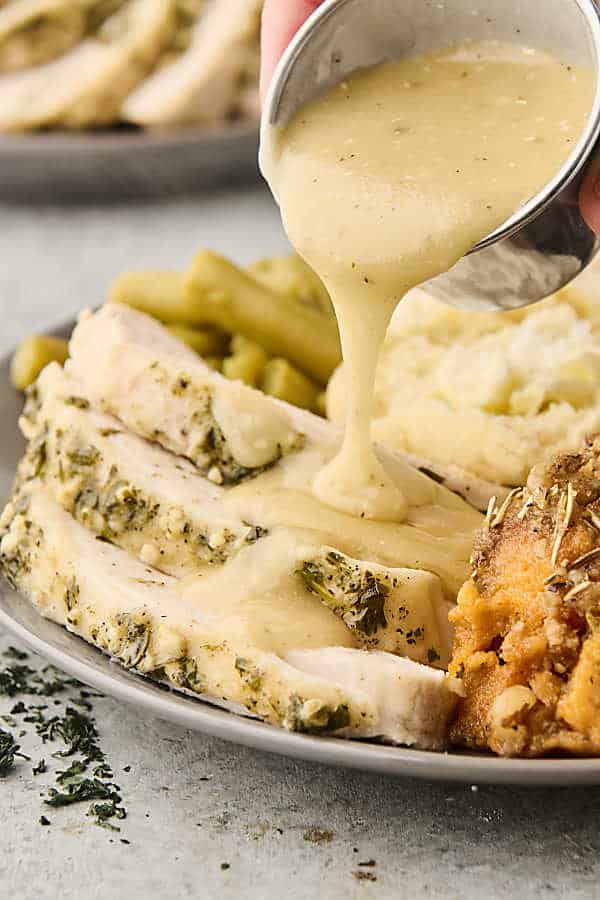 pouring gravy over sliced turkey
