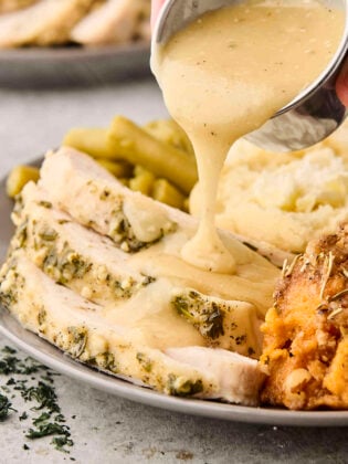pouring gravy over sliced slow cooker turkey breast