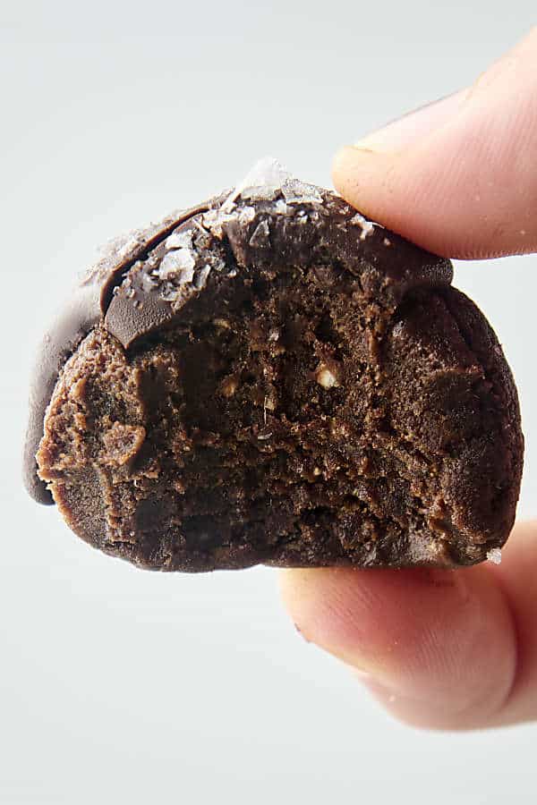 holding a chocolate date bite with a bite to show chewy texture