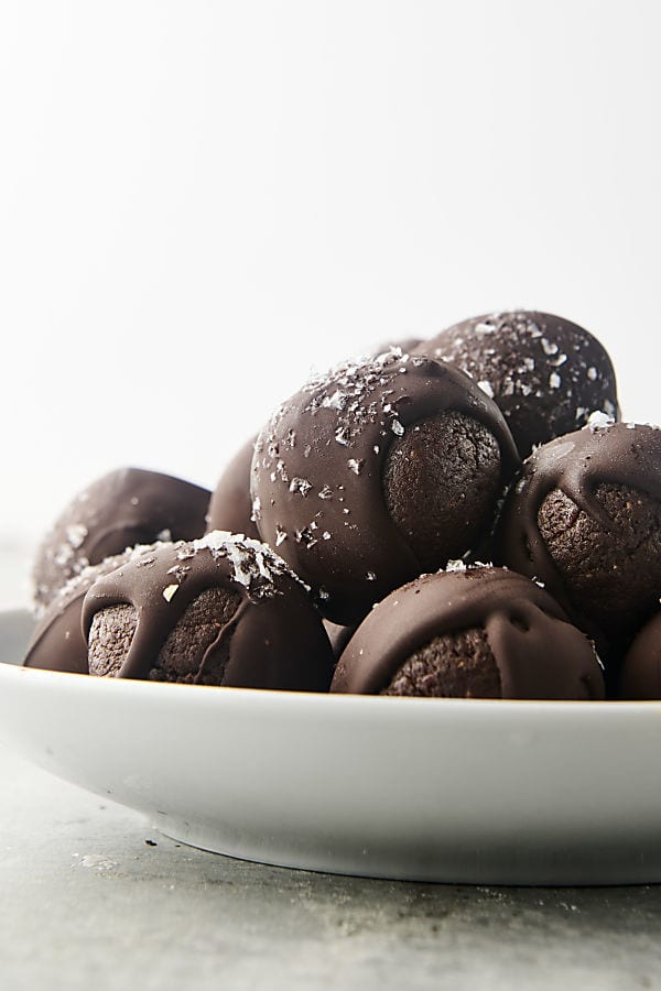 no-bake date balls on plate topped with chocolate and sea salt