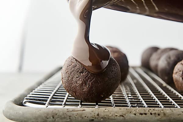 pouring melted chocolate onto date balls
