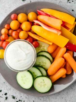 high protein cottage cheese ranch on a plate with cucumber, carrots, tomatoes, and peppers