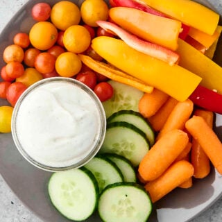 high protein cottage cheese ranch on a plate with cucumber, carrots, tomatoes, and peppers