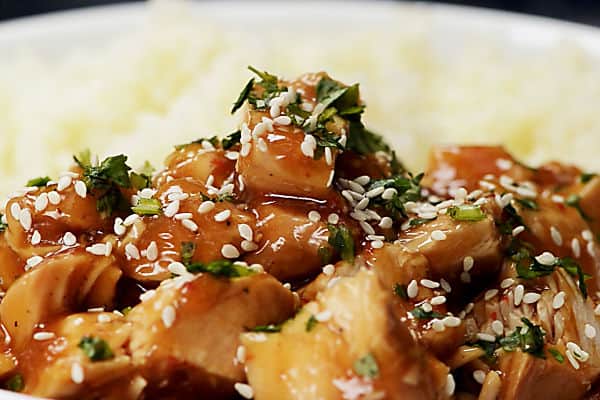 serving honey sesame chicken with cilantro and sesame seeds next to rice