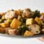 holding a plate of roasted chicken sausage with vegetables