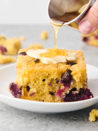 drizzling butter topped blueberry cornbread with honey