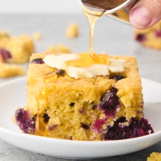 drizzling butter topped blueberry cornbread with honey