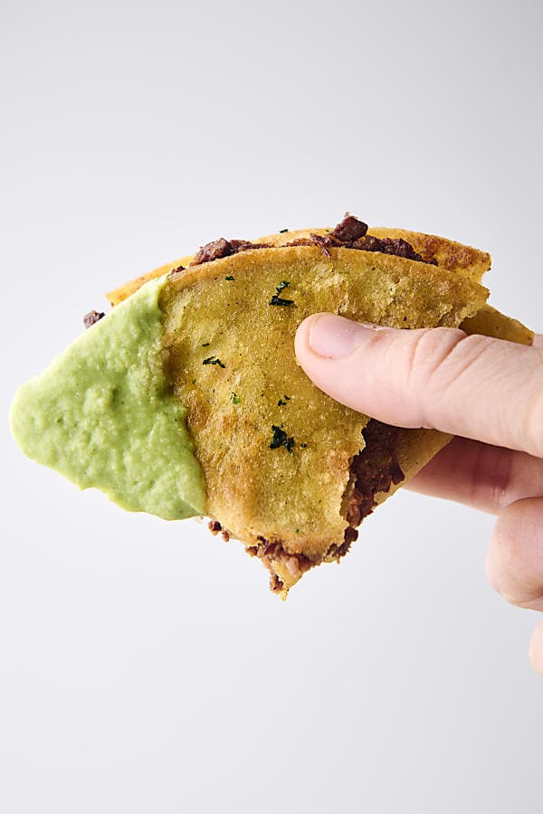 holding a black bean taco with cilantro lime sauce