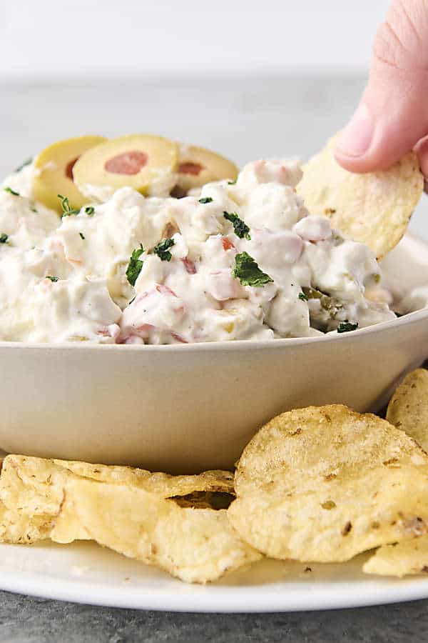 dipping a chip into dirty martini dip