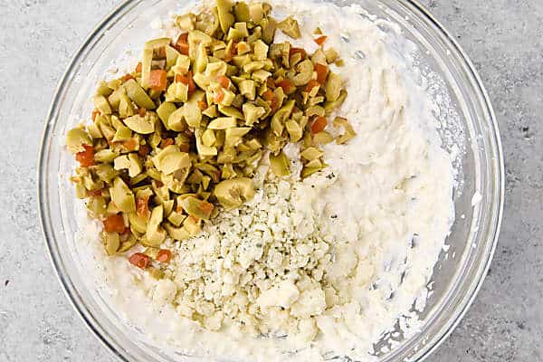 stirring olives and blue cheese into dirty martini dip