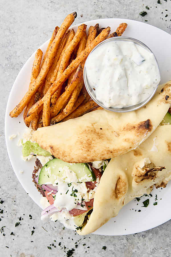gyro on a plate with sweet potato fries and tzatziki