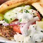 gryo on a plate with tzatziki and fresh vegetables