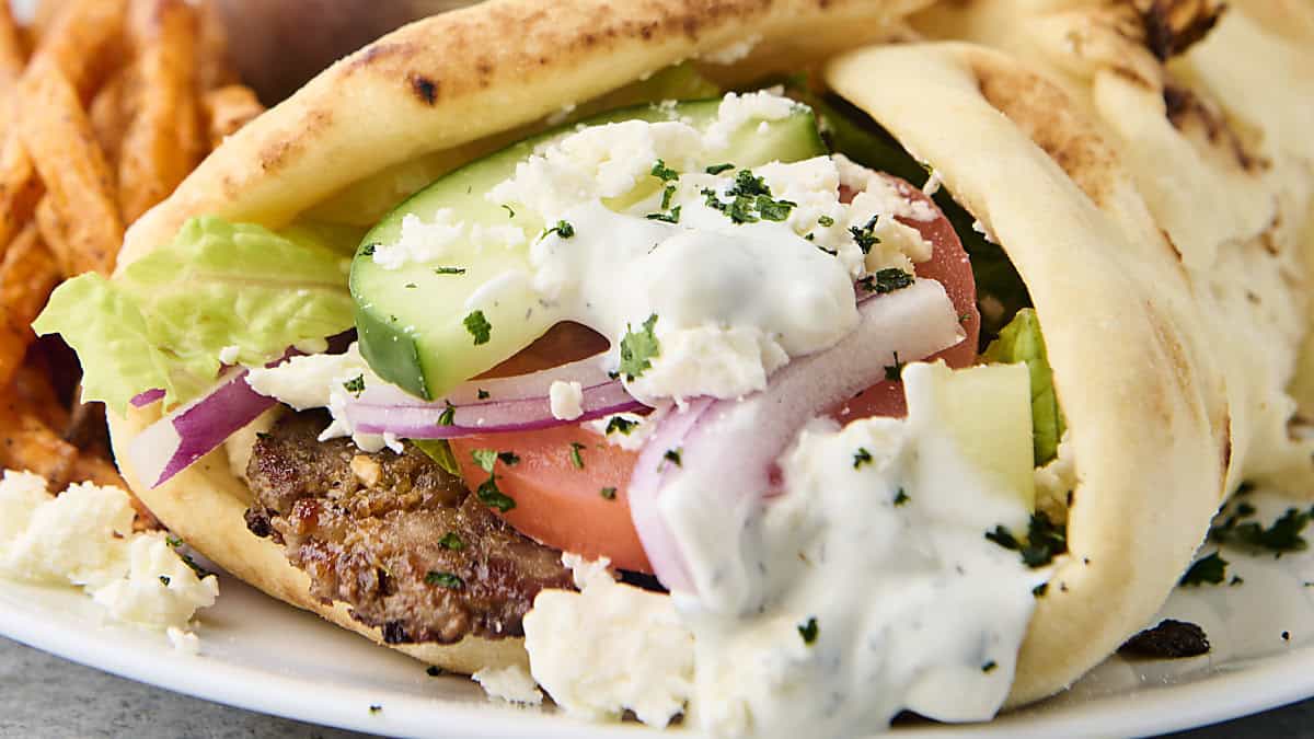 gryo on a plate with tzatziki and fresh vegetables