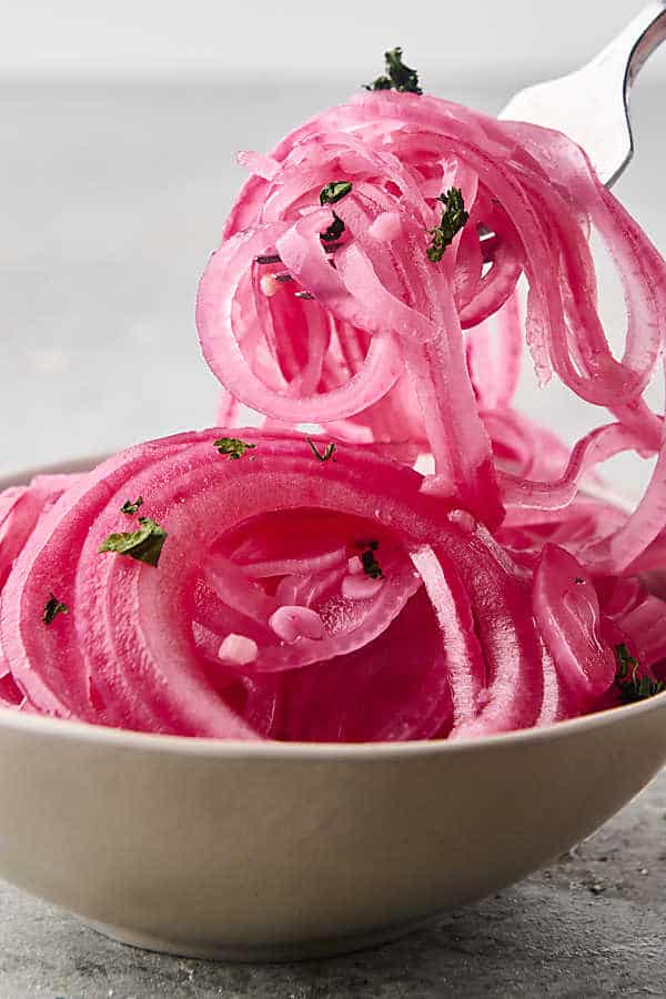 scooping quick pickled onions up with a fork