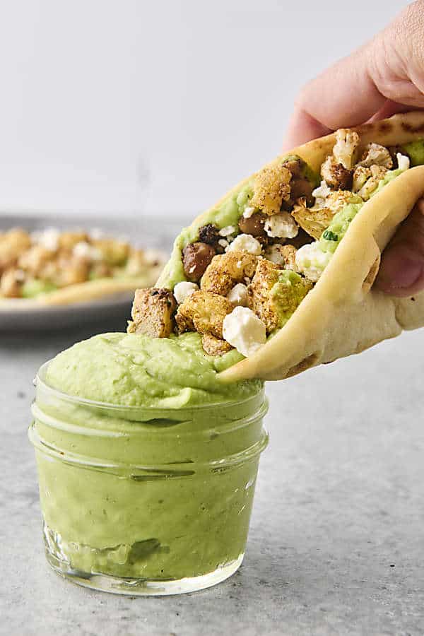 dunking a roasted veggie pita into avocado sauce
