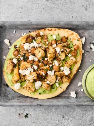 roasted cauliflower and chickpea pita on a tray with avocado sauce