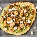 roasted cauliflower and chickpea pitas on a tray with avocado sauce