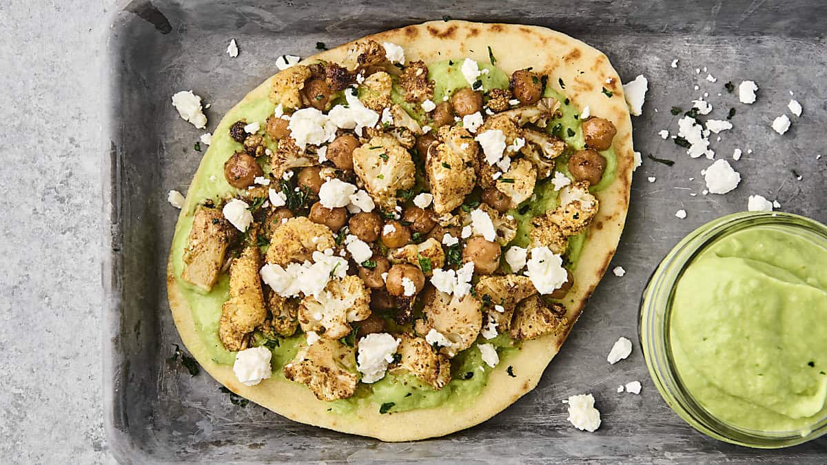 roasted cauliflower and chickpea pitas on a tray with avocado sauce