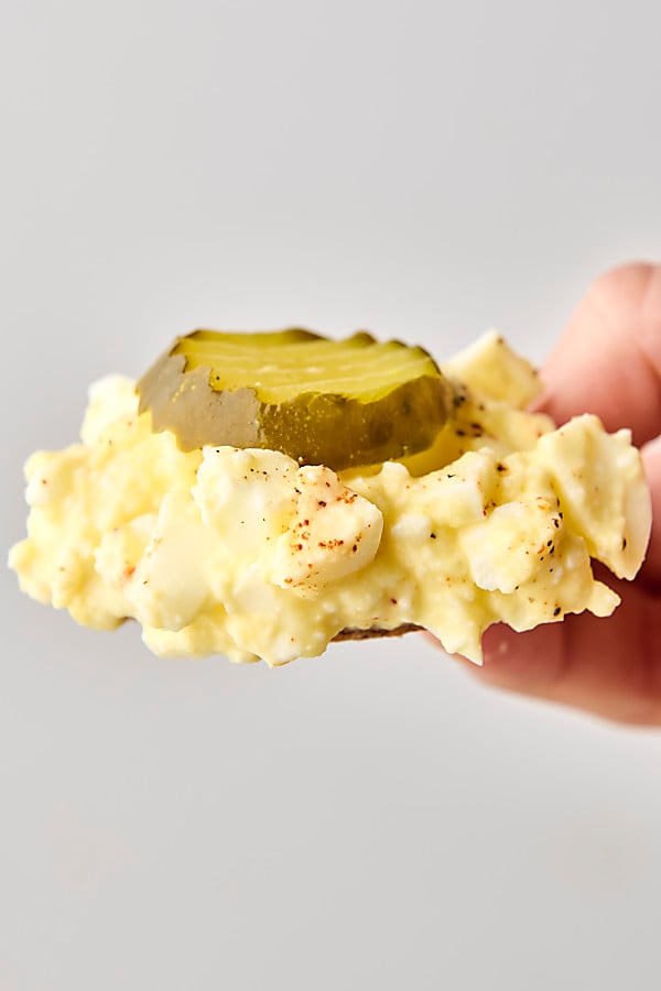 cottage cheese egg salad on a cracker topped with a pickle