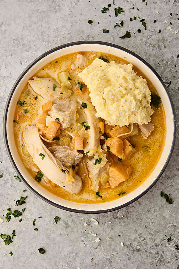 classic chicken stew in a bowl topped with a biscuit