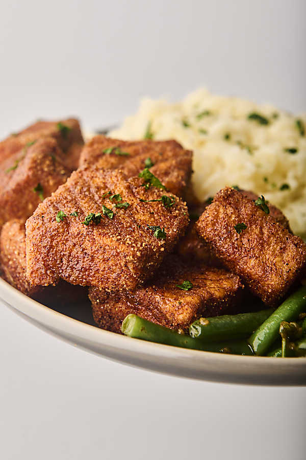 holding a plate of salmon with rice and green beans